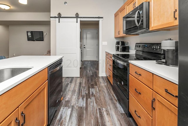 kitchen with dark wood-type flooring, a barn door, and black appliances