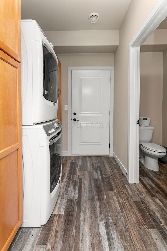 laundry area with stacked washer / dryer and dark hardwood / wood-style flooring