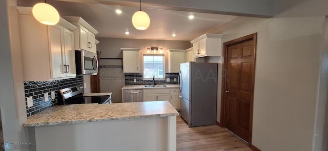 kitchen featuring light hardwood / wood-style flooring, stainless steel appliances, backsplash, decorative light fixtures, and white cabinetry