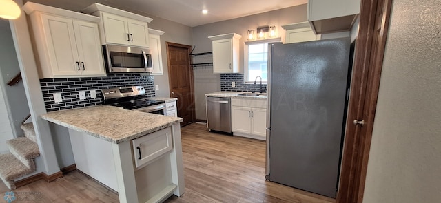 kitchen featuring white cabinetry, tasteful backsplash, stainless steel appliances, and light hardwood / wood-style floors