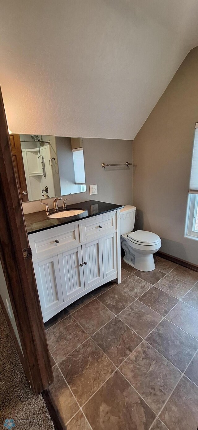 bathroom with tile patterned floors, vanity, lofted ceiling, and toilet