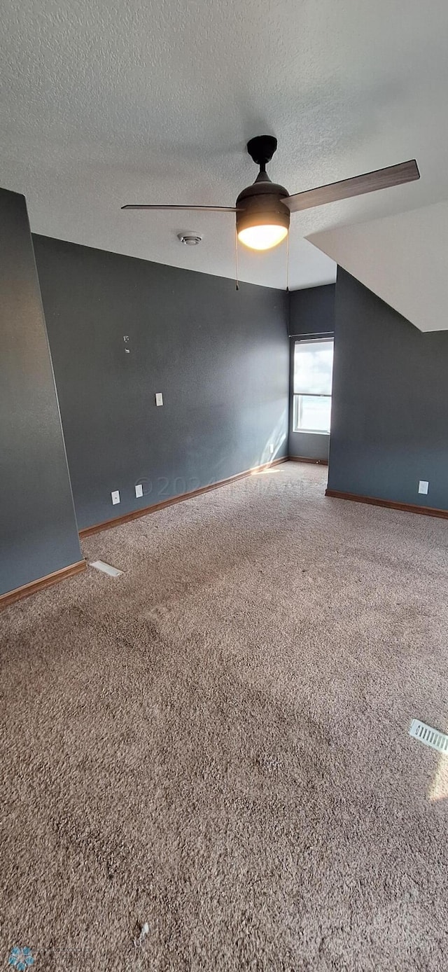 carpeted spare room featuring a textured ceiling and ceiling fan