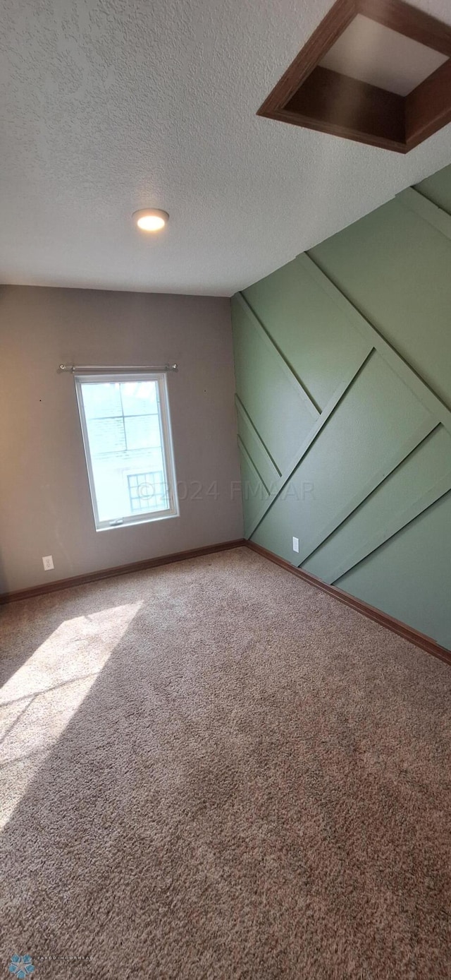 carpeted spare room with a textured ceiling