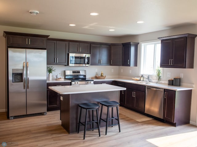 kitchen featuring sink, a kitchen bar, a kitchen island, light hardwood / wood-style flooring, and appliances with stainless steel finishes