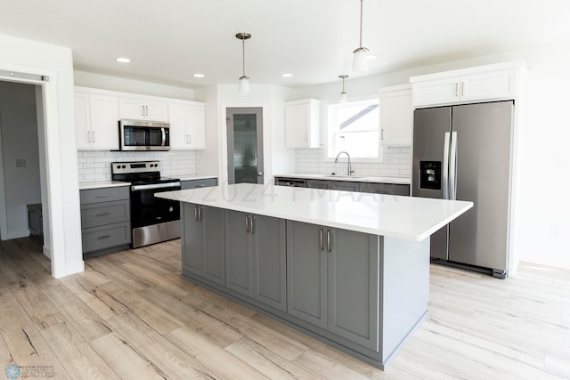 kitchen featuring hanging light fixtures, gray cabinets, stainless steel appliances, white cabinets, and a center island