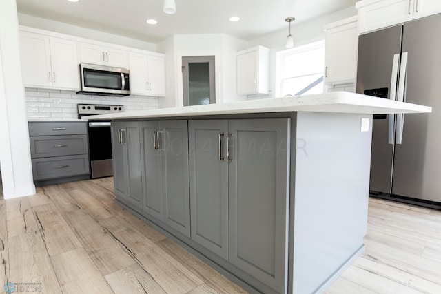 kitchen featuring hanging light fixtures, light hardwood / wood-style flooring, stainless steel appliances, and gray cabinets