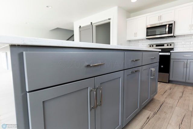 kitchen featuring electric stove, white cabinets, light hardwood / wood-style floors, tasteful backsplash, and gray cabinetry