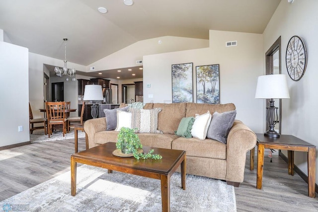 living room featuring a notable chandelier, light hardwood / wood-style flooring, and lofted ceiling