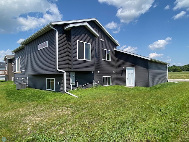 rear view of property with central AC unit and a yard