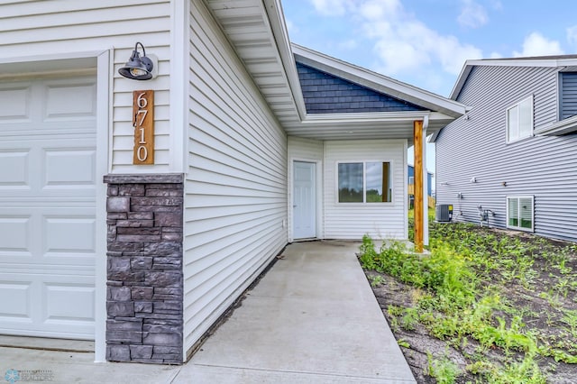 doorway to property with central air condition unit and a garage