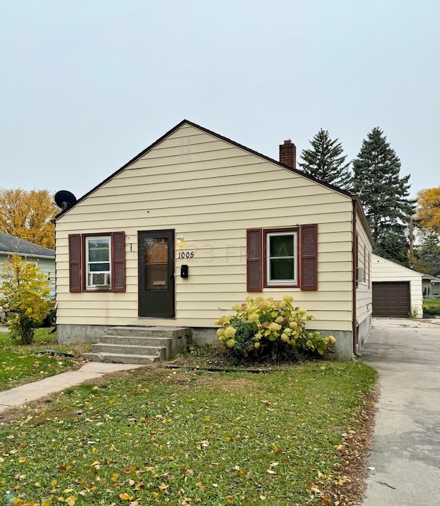 bungalow-style home with an outdoor structure, a garage, and a front yard