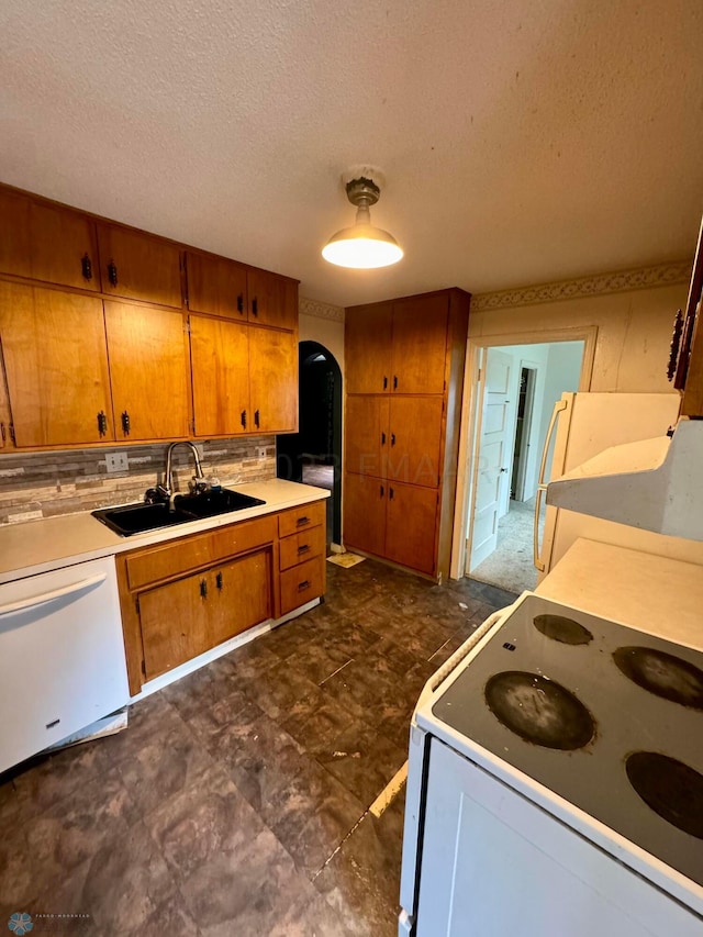 kitchen featuring white appliances, sink, tasteful backsplash, dark tile flooring, and a textured ceiling