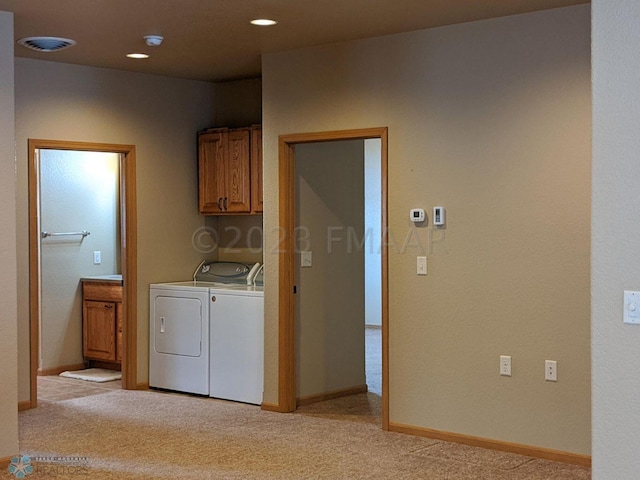 laundry room with light carpet, washing machine and clothes dryer, and cabinets