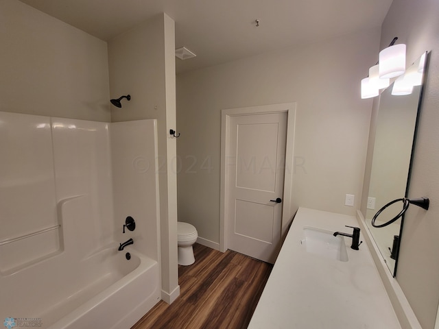 full bathroom with wood-type flooring, vanity, tub / shower combination, and toilet