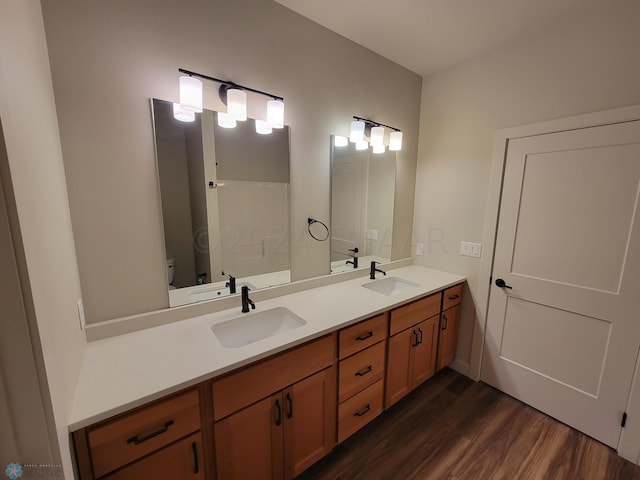 bathroom with wood-type flooring, toilet, and dual vanity