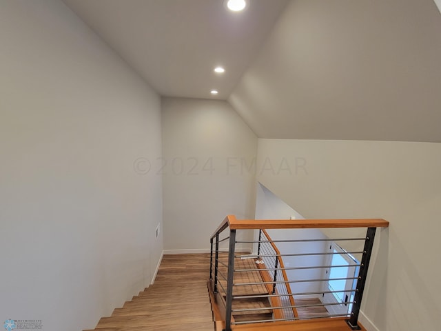 stairway with wood-type flooring and lofted ceiling