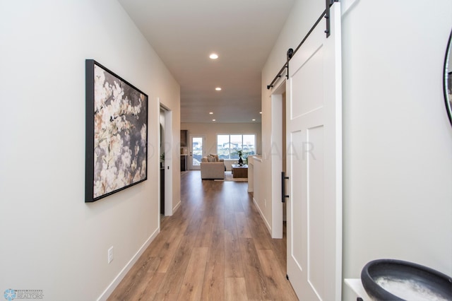 corridor with a barn door and light hardwood / wood-style flooring