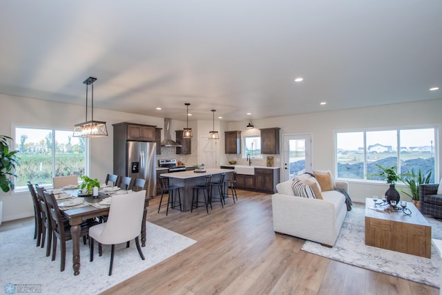 dining area with sink, light hardwood / wood-style floors, a chandelier, and a wealth of natural light