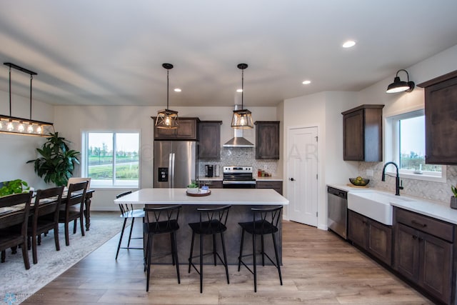 kitchen featuring a center island, pendant lighting, backsplash, stainless steel appliances, and light hardwood / wood-style floors