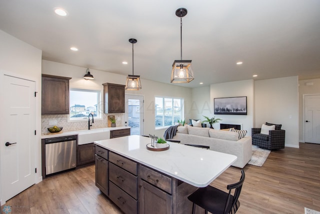 kitchen with a kitchen island, sink, dishwasher, backsplash, and light wood-type flooring