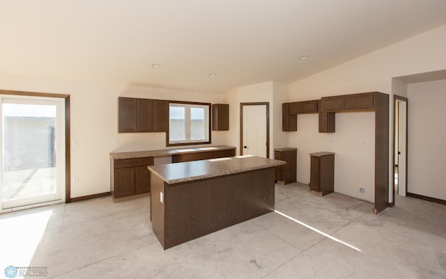 kitchen featuring a center island, lofted ceiling, and dark brown cabinetry