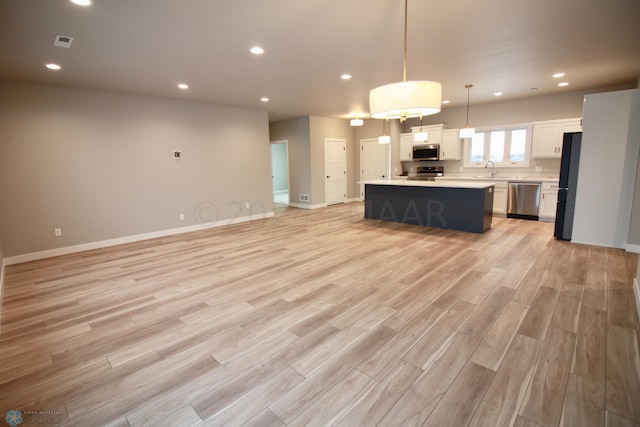 kitchen with a center island, light hardwood / wood-style floors, stainless steel appliances, and decorative light fixtures