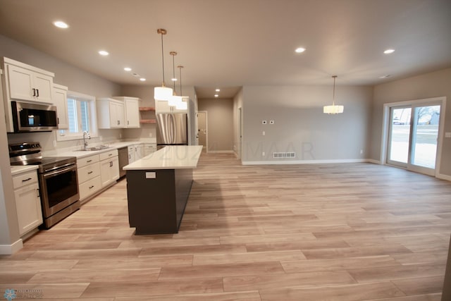 kitchen featuring appliances with stainless steel finishes, a healthy amount of sunlight, white cabinetry, and pendant lighting