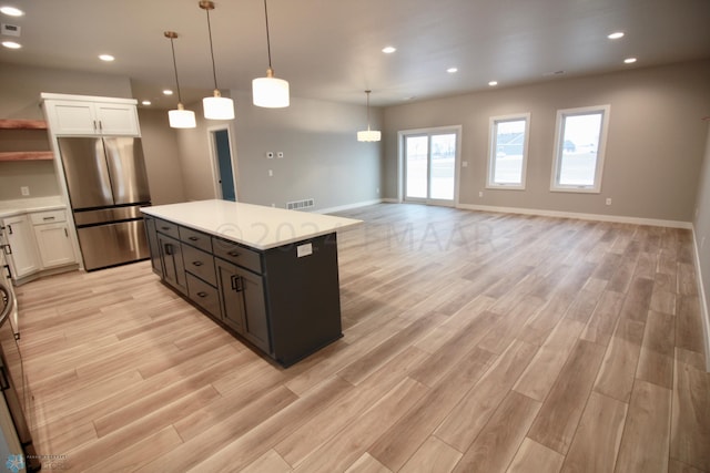 kitchen featuring stainless steel fridge, white cabinets, and light wood-type flooring