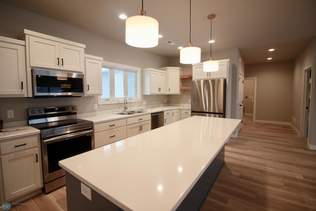 kitchen with a kitchen island, appliances with stainless steel finishes, wood-type flooring, and sink