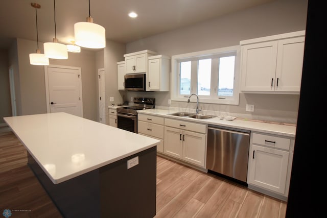 kitchen featuring pendant lighting, white cabinets, light hardwood / wood-style flooring, stainless steel appliances, and sink