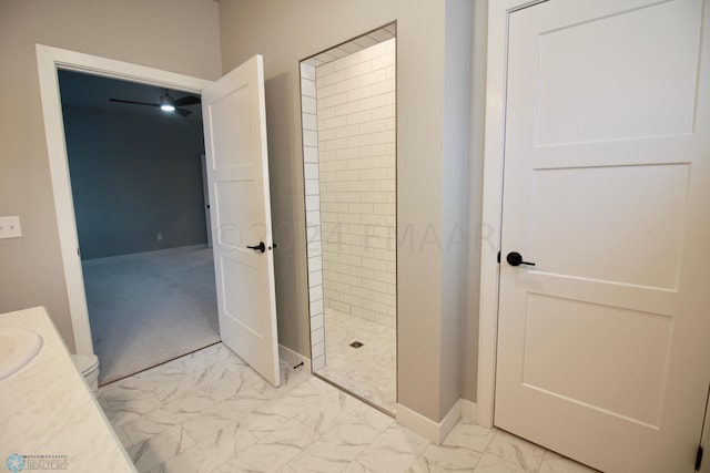 bathroom featuring a tile shower, vanity, toilet, and tile floors