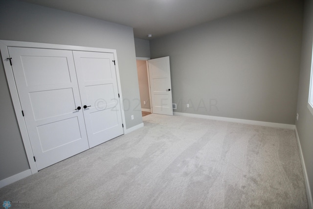 unfurnished bedroom with light colored carpet and a closet