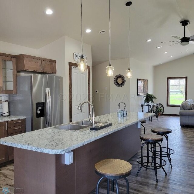 kitchen with pendant lighting, dark wood-type flooring, a center island with sink, ceiling fan, and lofted ceiling