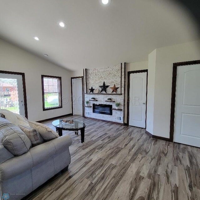 living room featuring wood-type flooring, lofted ceiling, and a large fireplace