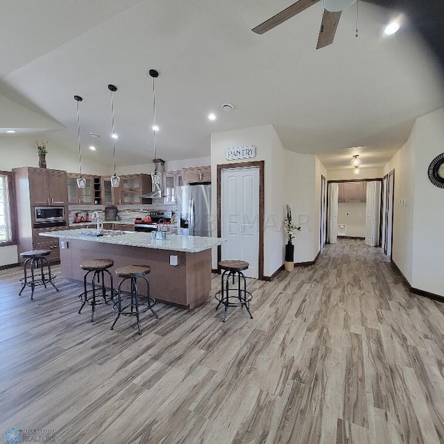 kitchen with stainless steel appliances, light wood-type flooring, a breakfast bar, and a large island