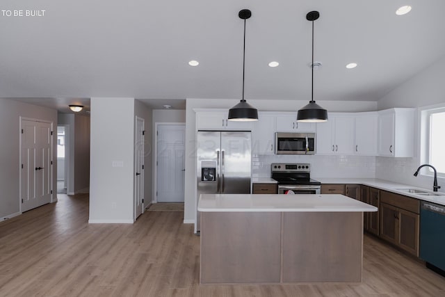 kitchen featuring light hardwood / wood-style flooring, sink, stainless steel appliances, and pendant lighting