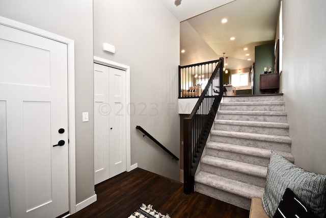 stairway with dark hardwood / wood-style flooring and vaulted ceiling