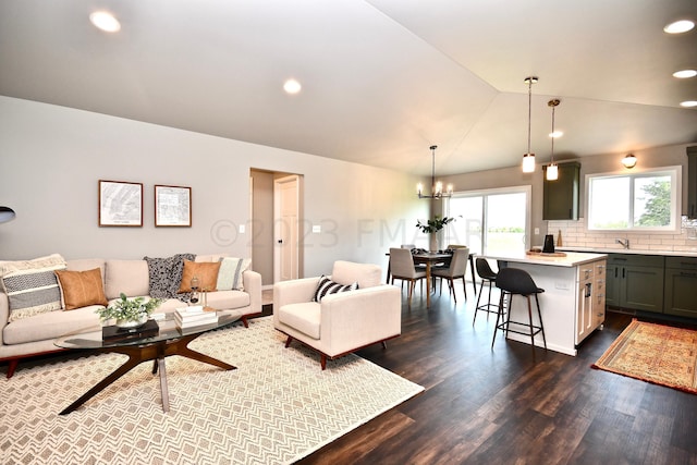 living room featuring a notable chandelier, lofted ceiling, and dark hardwood / wood-style floors