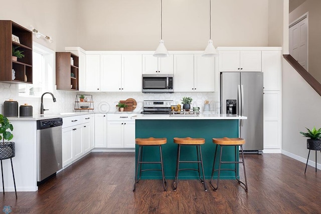 kitchen featuring a center island, tasteful backsplash, stainless steel appliances, and dark wood-type flooring