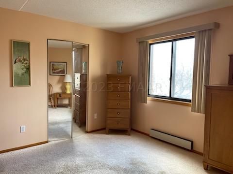 bedroom with light carpet, a baseboard radiator, and a textured ceiling