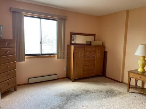 bedroom with light colored carpet and a baseboard radiator