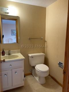 bathroom featuring vanity with extensive cabinet space, toilet, and tile flooring