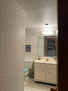 bathroom featuring tile flooring, oversized vanity, toilet, and a textured ceiling