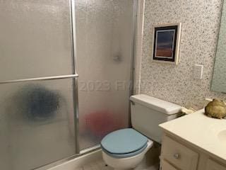 bathroom with a shower with door, vanity, and toilet