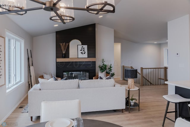 living room featuring light hardwood / wood-style flooring, a notable chandelier, and lofted ceiling