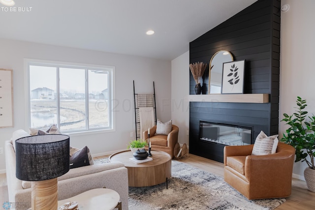 living room with a fireplace, light hardwood / wood-style flooring, and vaulted ceiling