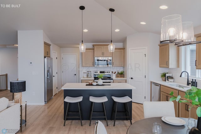 kitchen with backsplash, light hardwood / wood-style floors, stainless steel appliances, and a kitchen island