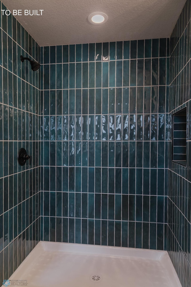 bathroom with tiled shower and a textured ceiling