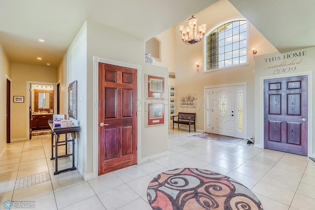 tiled entrance foyer featuring a chandelier and a towering ceiling