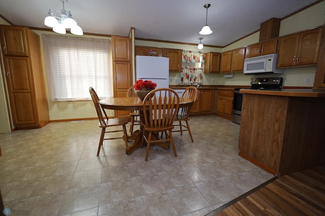 kitchen featuring pendant lighting, vaulted ceiling, an inviting chandelier, white appliances, and crown molding